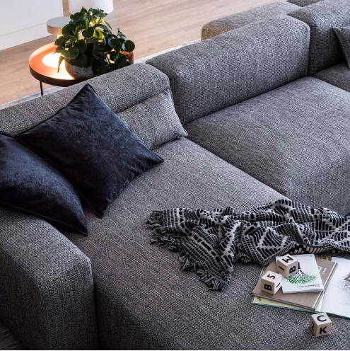 Grå modulsoffa med kuddar och pläd